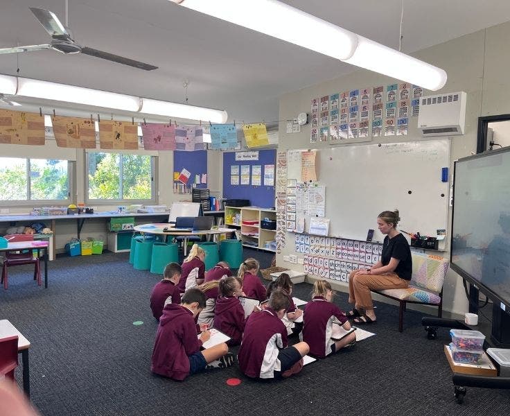 The K-2 class sitting on floor with teacher, showing the large bright classroom