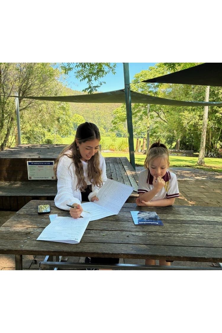 A young female student and our SLSO sitting outside doing individual learning