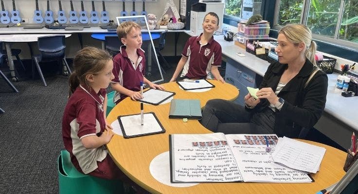 our principal sitting at a small table with three students doing lesson