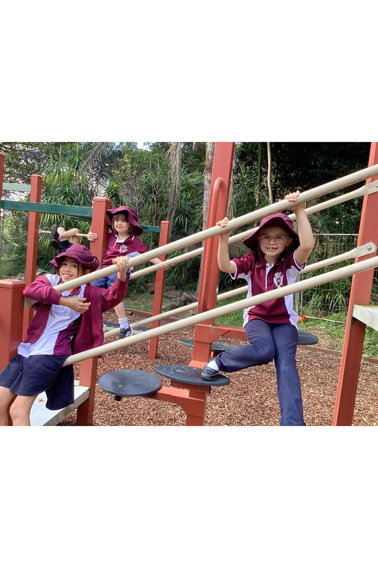 three students hanging on playground equipment