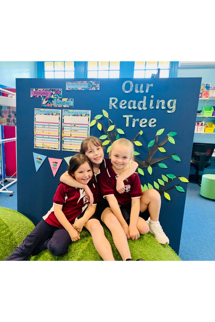 Three students sitting on mound seat in the library looking at camera