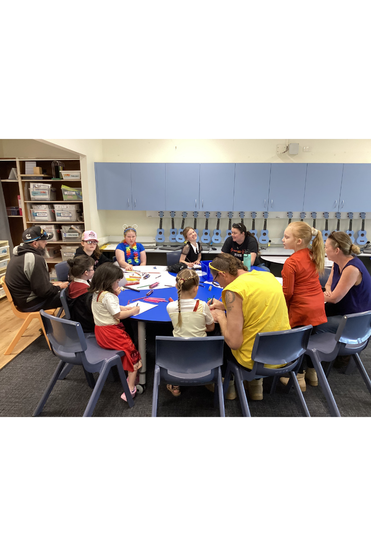 Family members and students sitting around a large round table involved in activities for Book Week